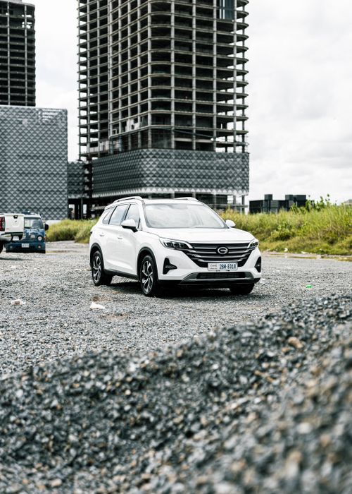 Free White SUV parked on construction site with unfinished high-rise buildings. Stock Photo