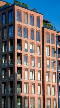 A vertical perspective of a modern brick apartment building with glass windows.