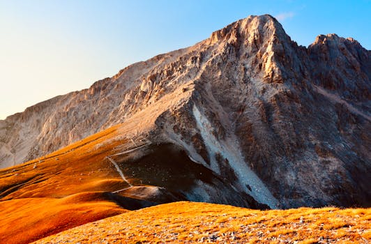 Stunning sunrise over Gran Sasso mountains, highlighting rocky peaks and vibrant orange slopes.