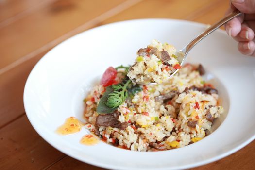 A mouthwatering dish of beef and vegetable risotto being served with a spoon.