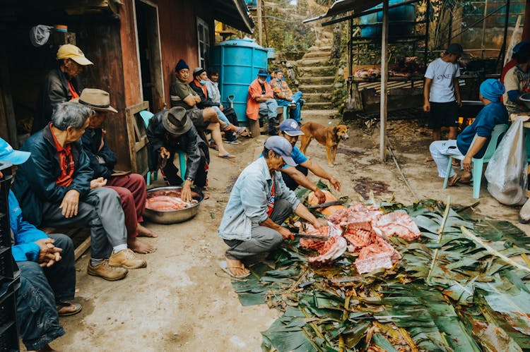 People Cutting Meat On A Street