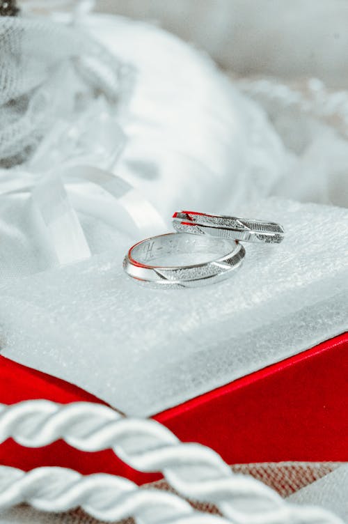 Silver Wedding Rings Lying on Small Pillow