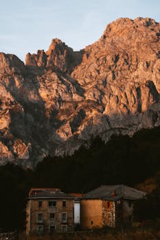 Scenic view of a rustic house in Spanish countryside against a rocky mountain backdrop.