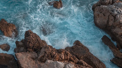 Ocean Waves Splashing on Brown Rocks