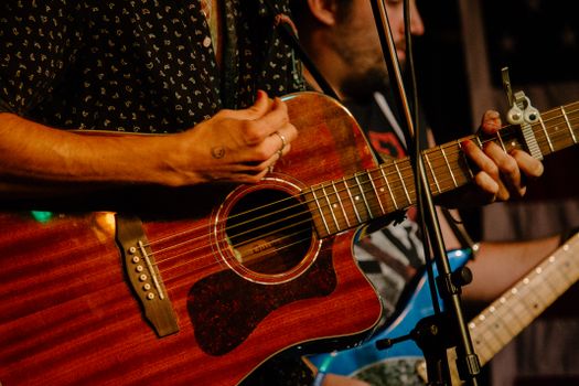 Hands playing an acoustic guitar during a live music performance in Boston.. hands, playing, acoustic