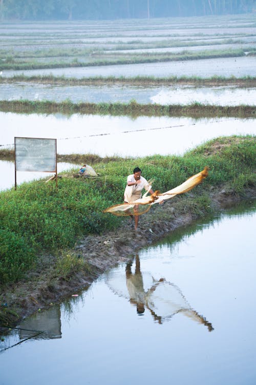 Man throwing Fishing Net on a Pond 