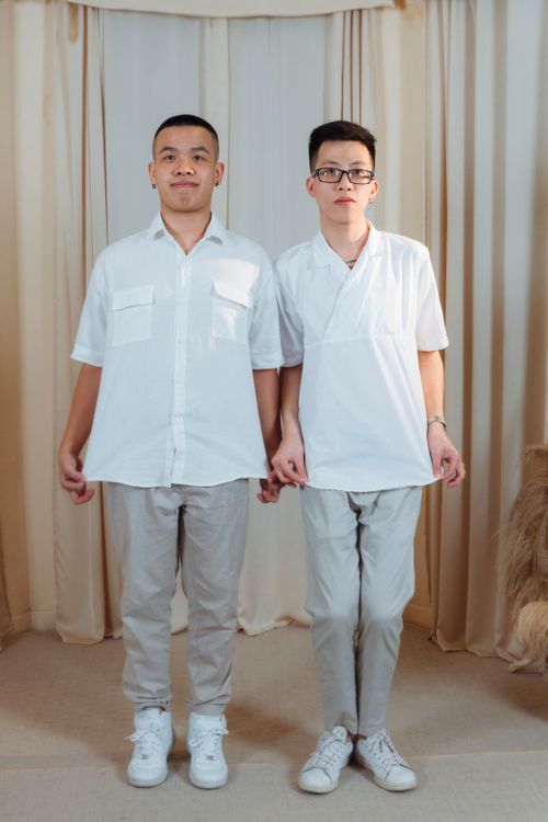 Free Two young men standing side by side indoors, holding hands, expressing friendship and support. Stock Photo