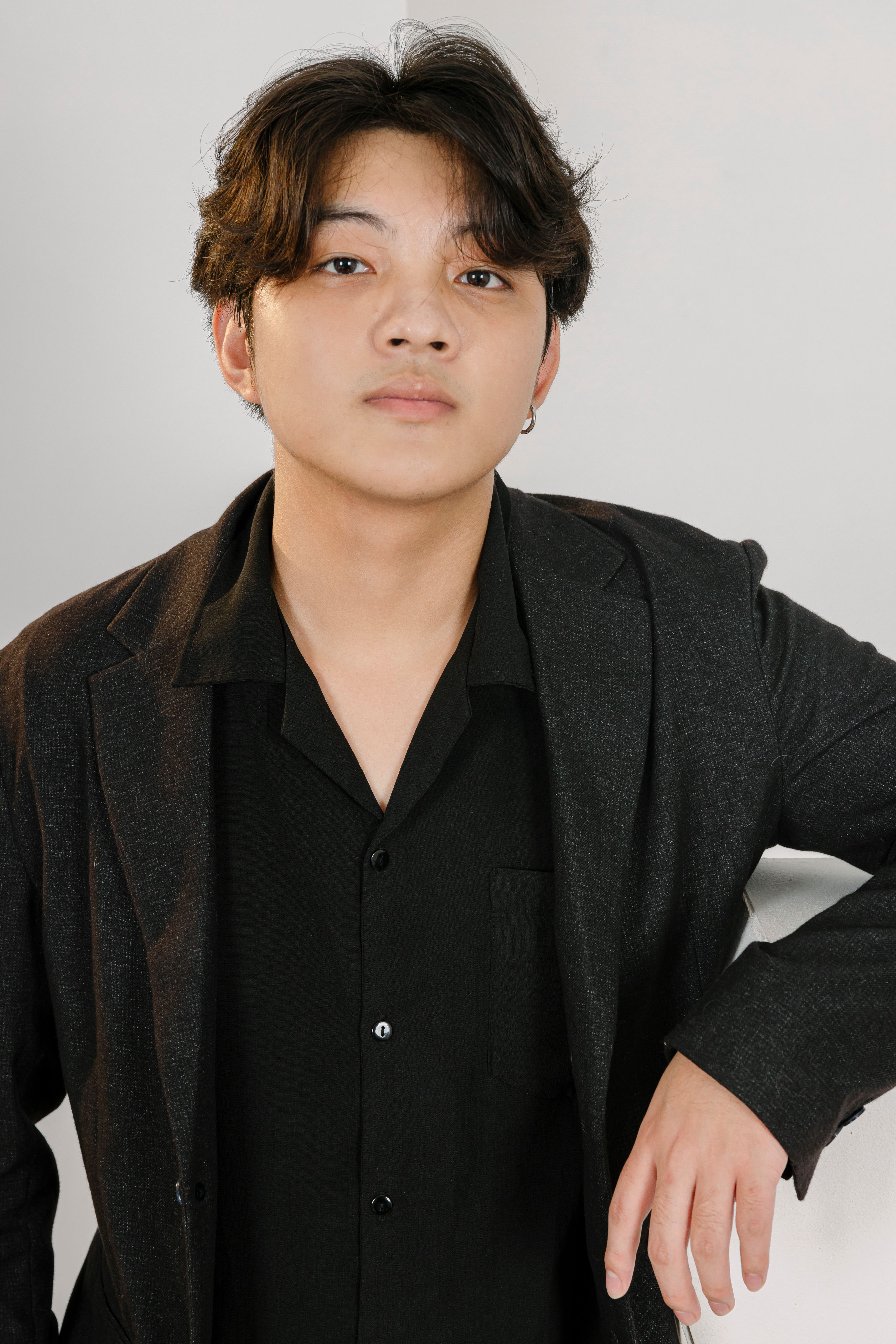Portrait of a confident young man in a black jacket against a neutral background.