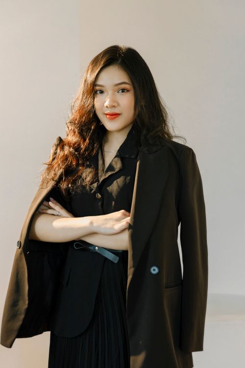 Free A portrait of a confident young woman wearing an elegant black blazer, captured in a studio setting. Stock Photo