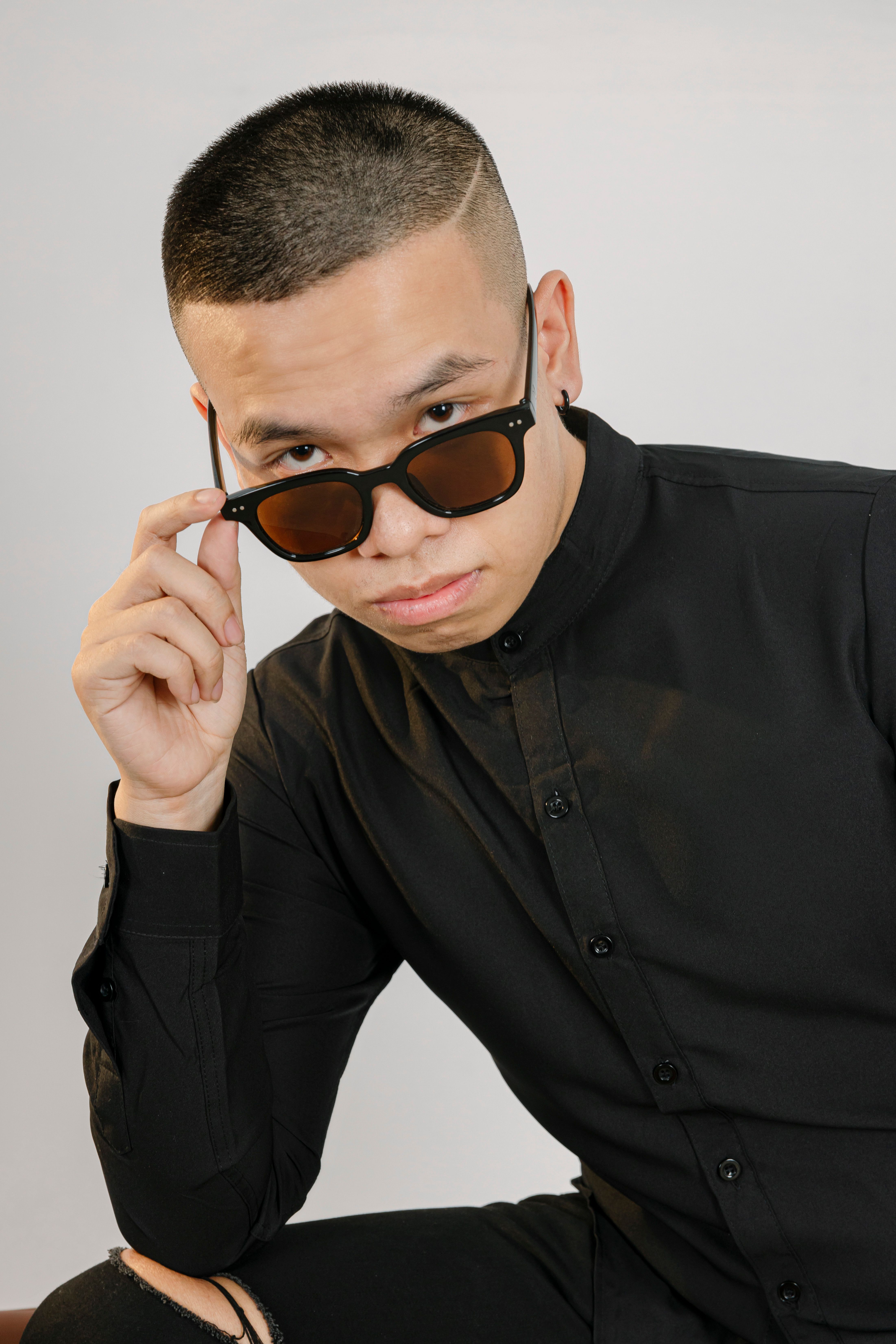 Young man in sunglasses and black shirt, posing against a white background.