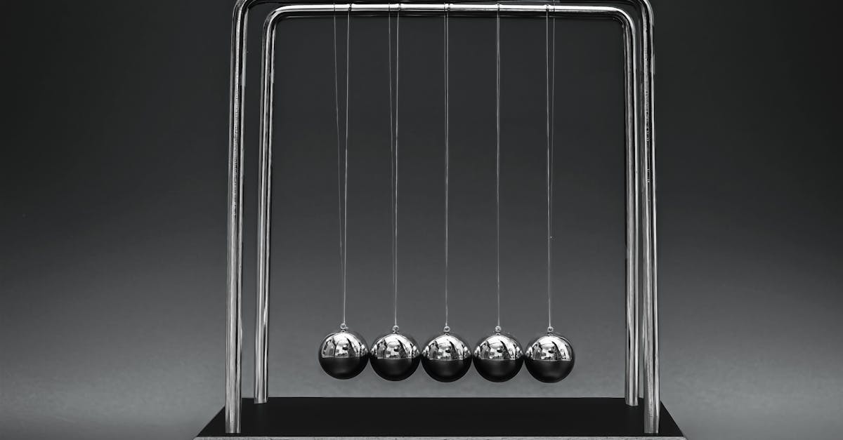 Close-up image of Newton's Cradle illustrating physics concepts on a dark gray background.