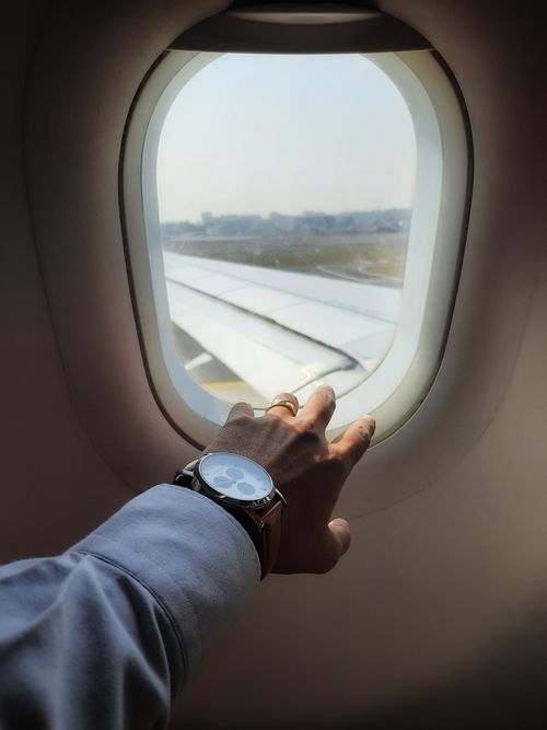 Free A person's hand with a wristwatch, reaching out the airplane window over Mumbai, capturing the plane wing view. Stock Photo
