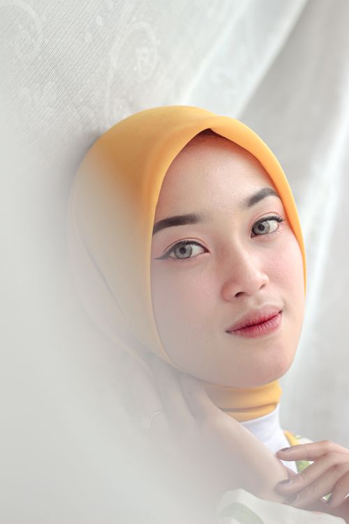 Free Slight smile on a woman wearing a yellow hijab, showcasing cultural fashion. Stock Photo