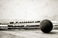 A Grayscale of of a Racket and Squash Ball