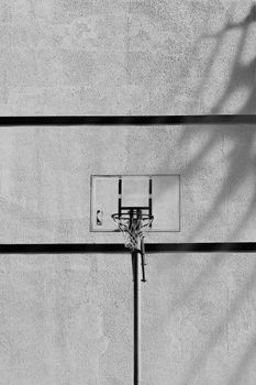 Black and white image of a basketball hoop on an outdoor concrete wall showcasing urban sports theme.