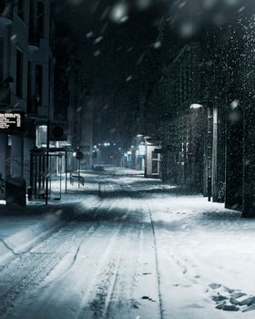 A quiet urban street covered in snow on a cold, winter night.