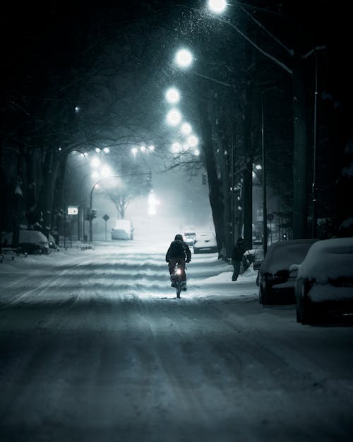 Foto profissional grátis de à noite, andando de bicicleta, carros estacionados