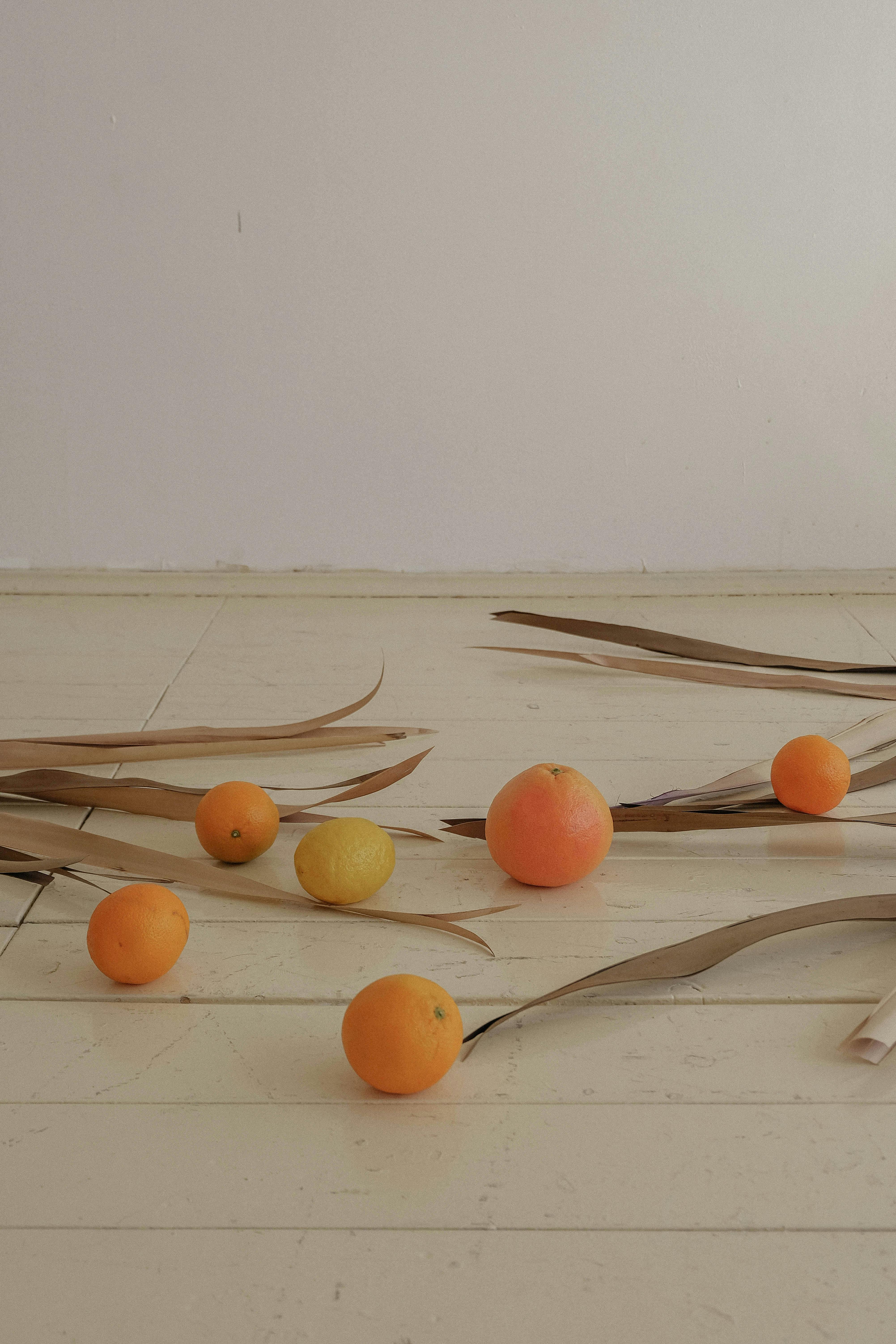 Elegant arrangement of oranges and lemons with leaves on light wooden floor.