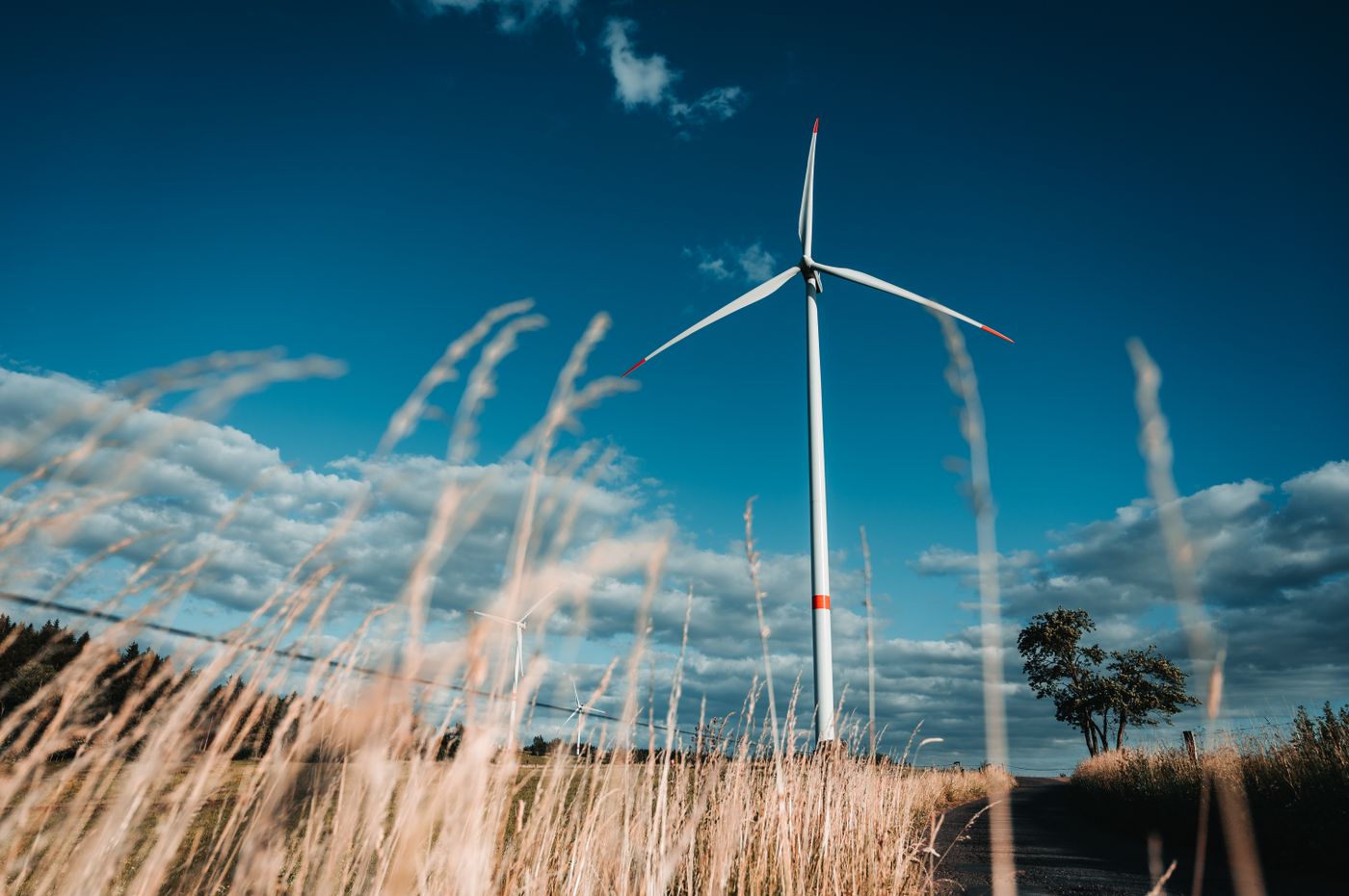 Wind turbine under a blue sky in a rural field, symbolizing renewable energy.