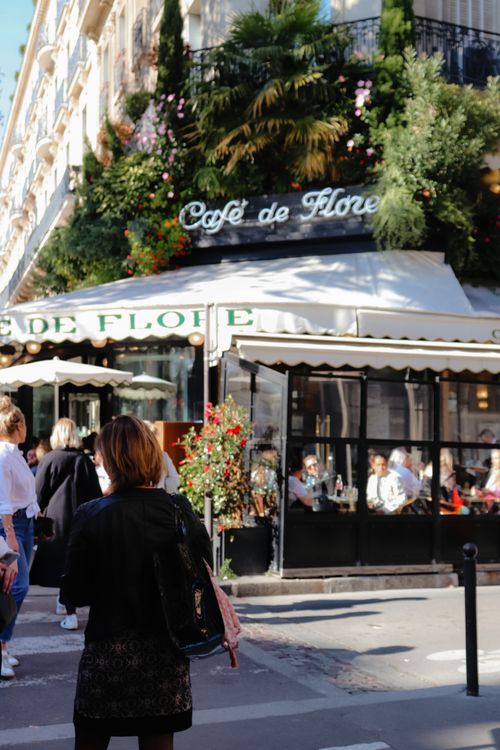 Free Lively street scene at Café de Flore in Paris, showcasing outdoor dining and iconic Parisian architecture. Stock Photo