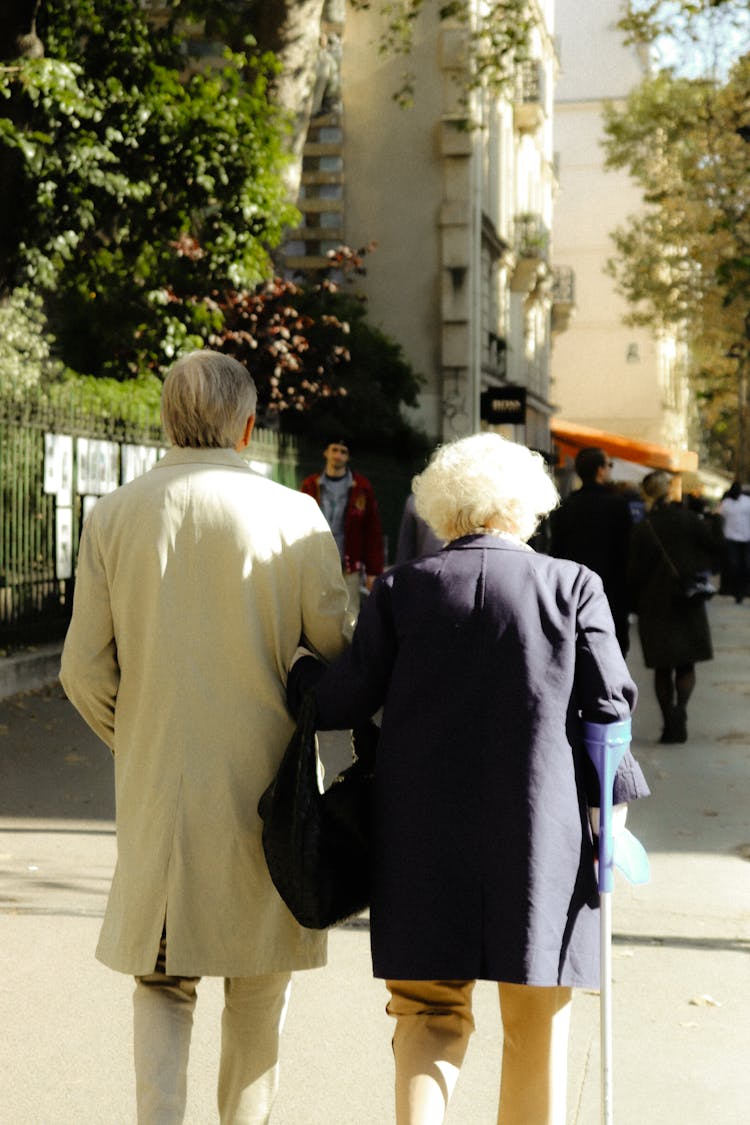 A Back View Of Elderly Couple Walking On The Street