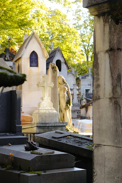 Free Cemetery with Statue of Woman and a Stone Cross Stock Photo