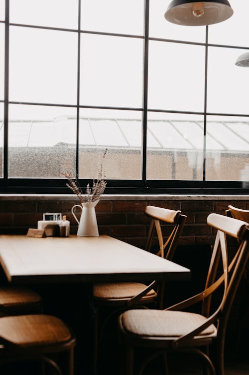 An Empty Wooden Table With Chairs Near the Glass Window