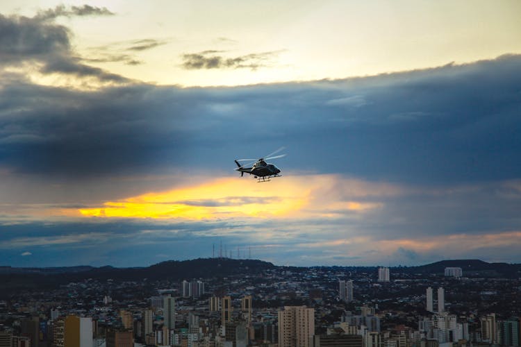 A Helicopter Flying Over City During Sunset