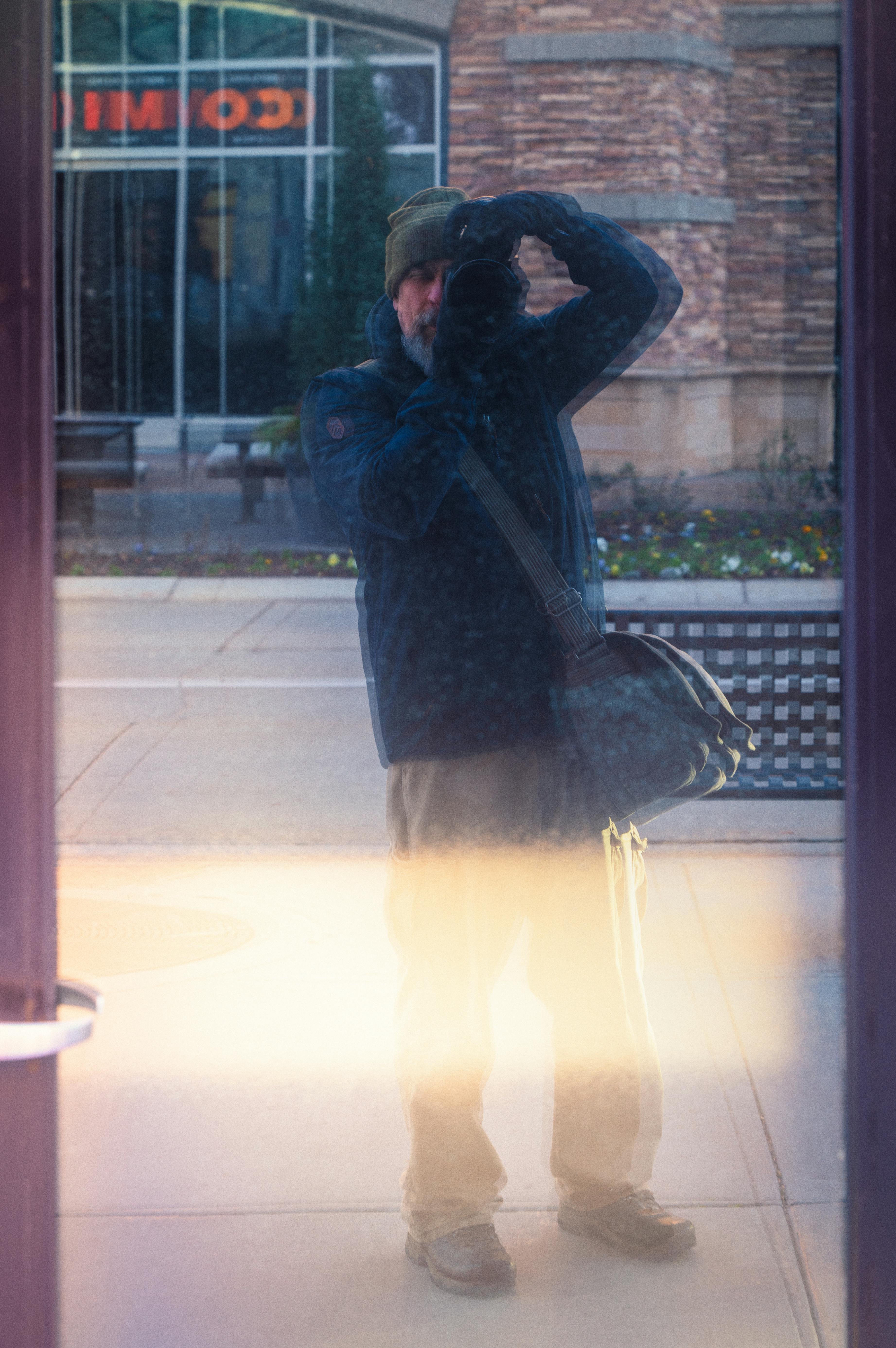 A reflection of a photographer capturing the cityscape in a mirror.