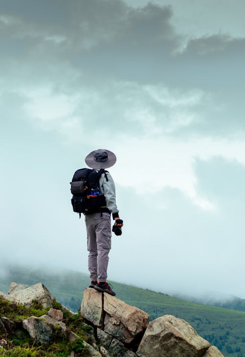 Free A Person Standing on the Rock while Carrying a Backpack Stock Photo