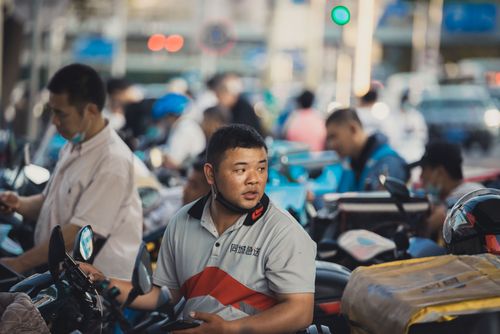 Free Street scene depicting delivery workers with motorcycles, bustling with activity. Stock Photo