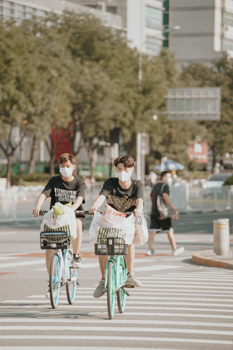 Young Men Cycling With Shopping Bags