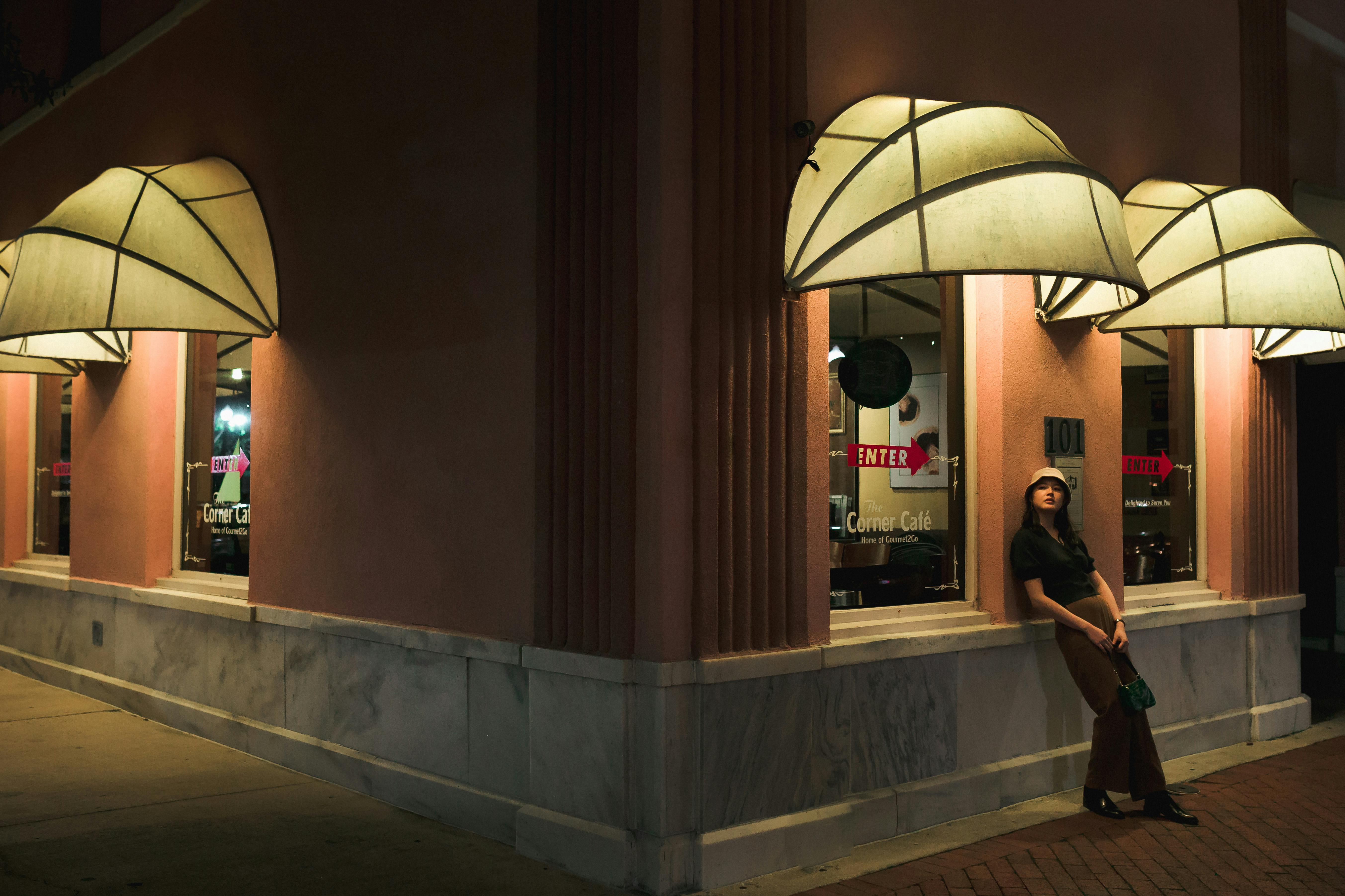 Free A woman leans against a storefront at night near the Corner Café in Sanford, Florida. Stock Photo