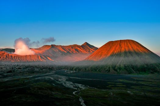 A breathtaking aerial view of Mount Bromo during sunrise with a vibrant sky and volcanic mist.