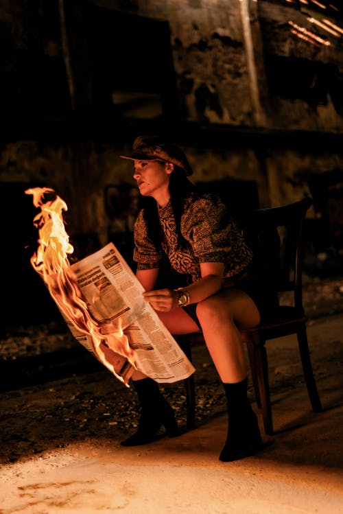 Free Woman sitting on Chair holding a Burning Newspaper  Stock Photo