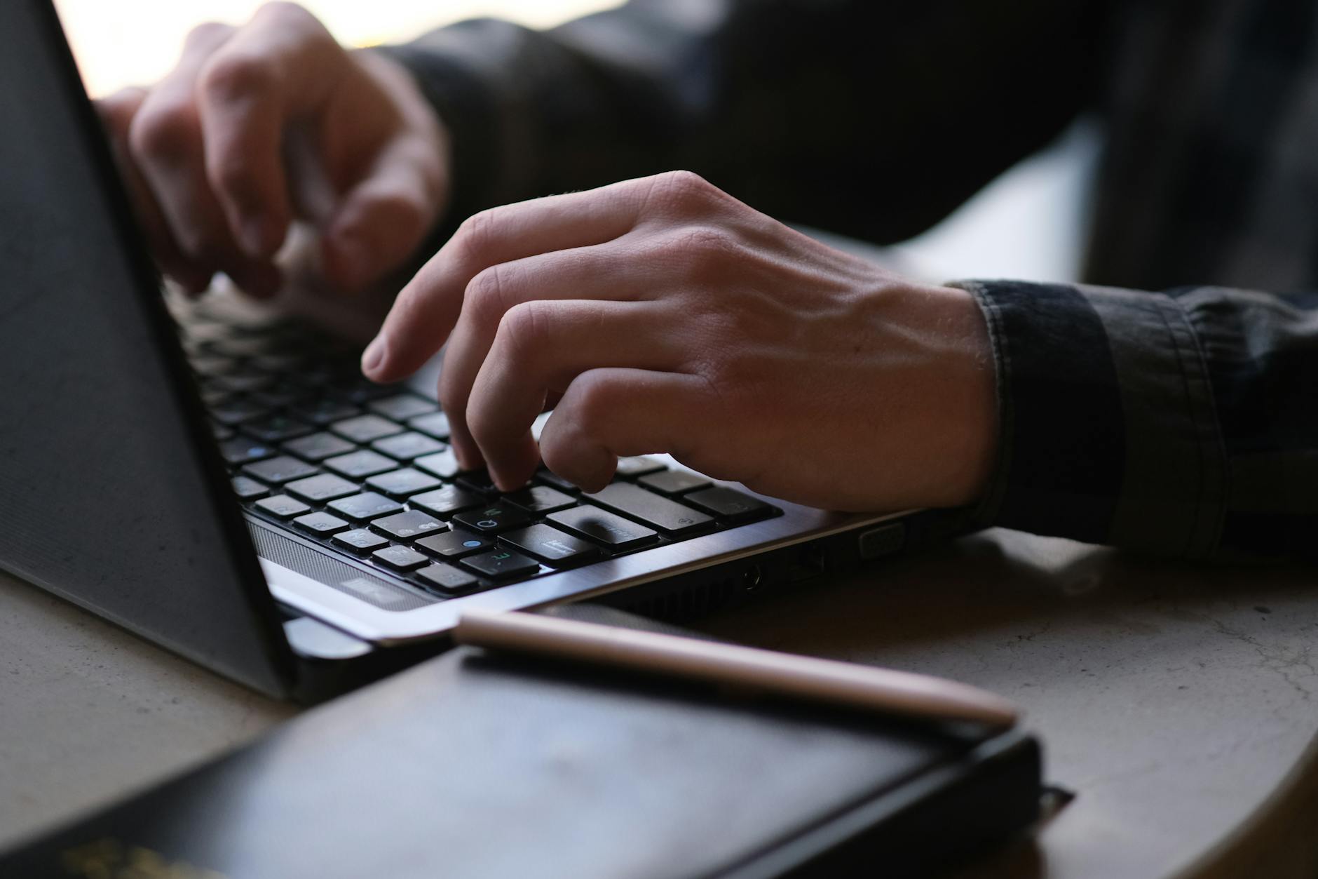 Close-up photo of hands typing on a laptop, perfect for remote work or digital nomad themes.