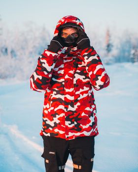 A person bundled in warm clothing stands in a snowy outdoor setting.