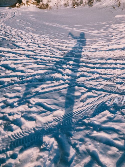 Free Artistic shadow on snow-covered ground marked with tire tracks, capturing winter essence. Stock Photo