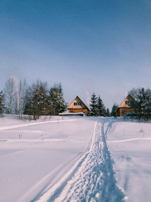 Free Two wooden cabins in a snowy landscape with clear blue skies. Perfect winter scene for tranquil retreats. Stock Photo