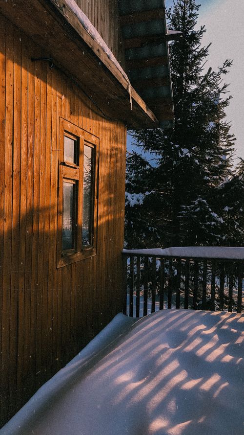 Free A cozy wooden cabin with snow-covered surroundings and sunlight streaming through. Stock Photo
