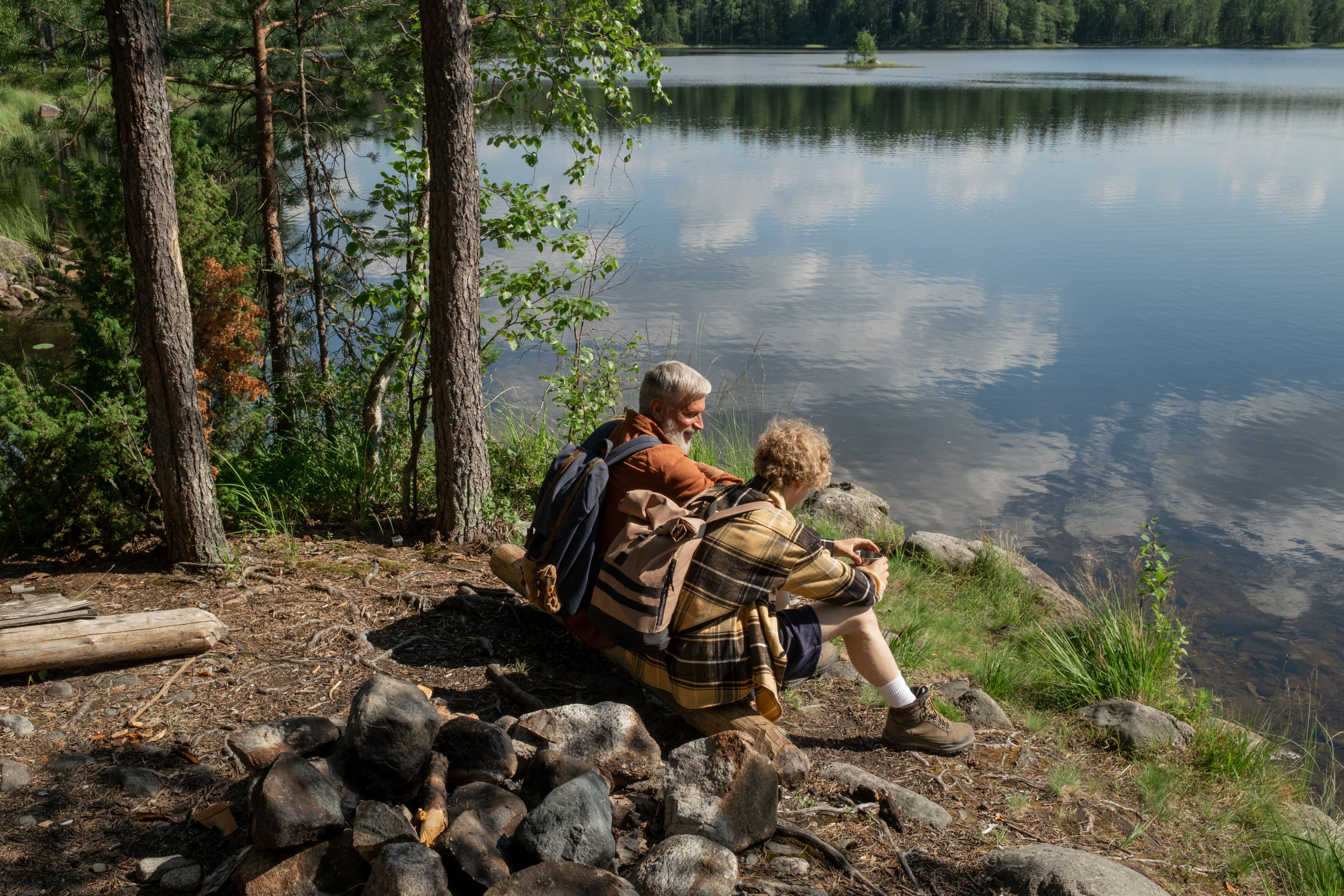 Grandfather and grandson enjoying a tranquil moment by a lakeside in nature.