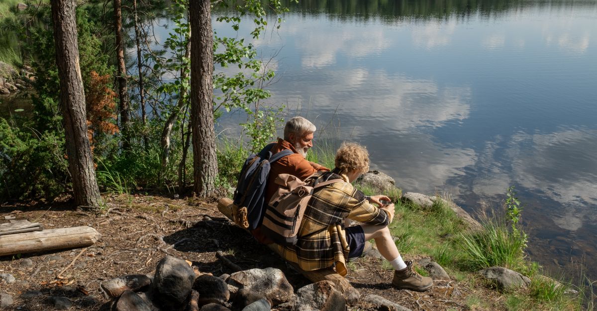 Grandfather and grandson enjoying a tranquil moment by a lakeside in nature.
