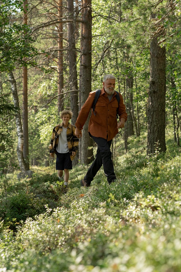 Elderly Man And A Teenage Boy Walking In The Woods