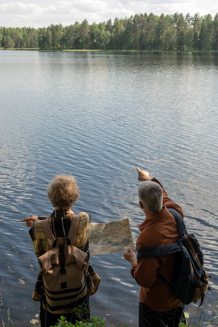 Grandfather With Grandson Hiking With Map By Lake