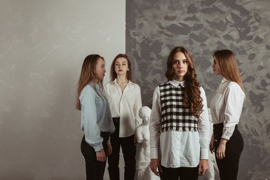 Stylish women in formalwear posing elegantly indoors with a classic sculpture backdrop.
