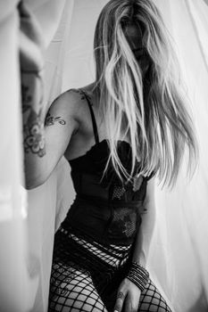Captivating monochrome image of a woman in lingerie with tattoos, creating an evocative mood.