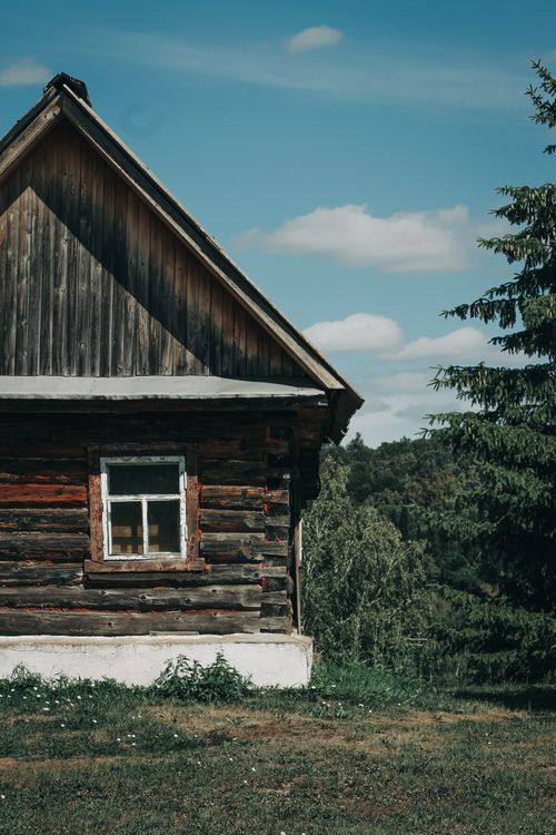 Free Charming wooden cabin nestled in a peaceful rural landscape under a bright blue sky. Stock Photo