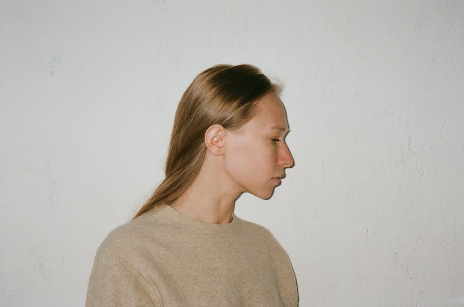 A serene side profile of a woman against a textured beige wall.