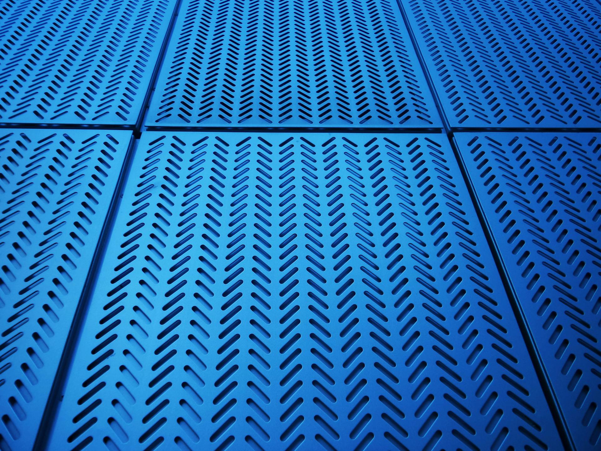 Geometric arrangement of blue metal panels with perforated design and copy space.