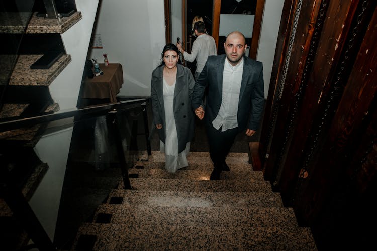 Man And Woman Holding Hands While Going Up The Stairs